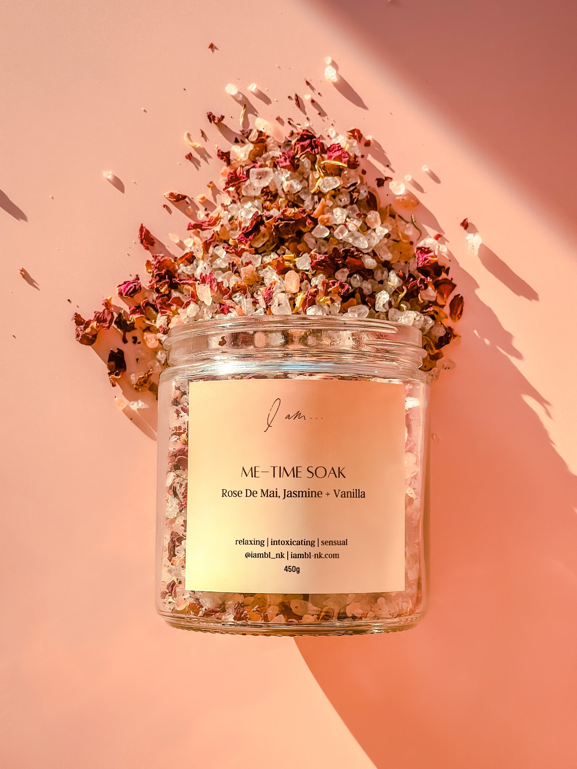 Me-Time Rose de mai soak, photo shows a jar flat lay with soak salts and petals pouring out of the jar